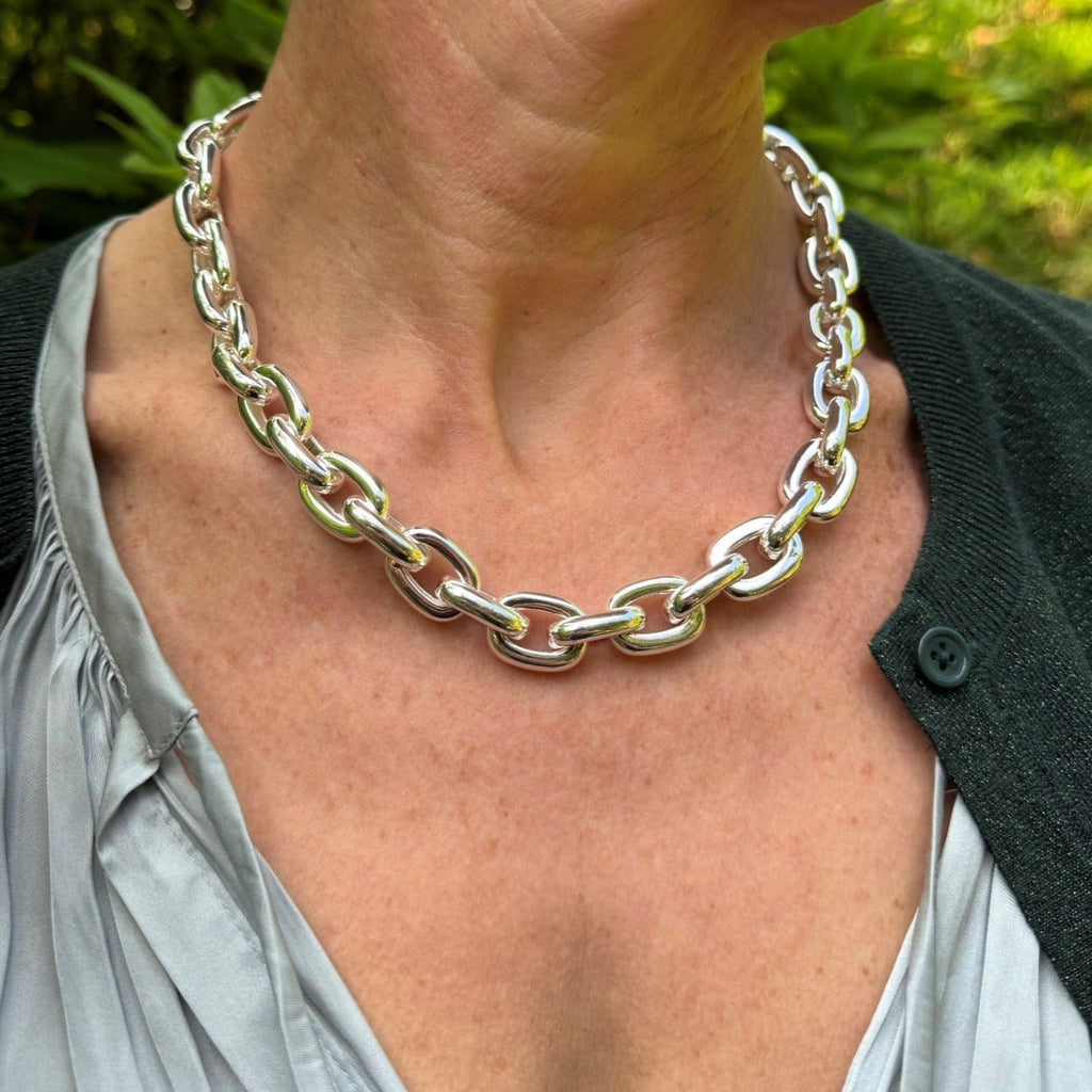 A supersize sterling silver paperclip style chain, worn on a models neck.