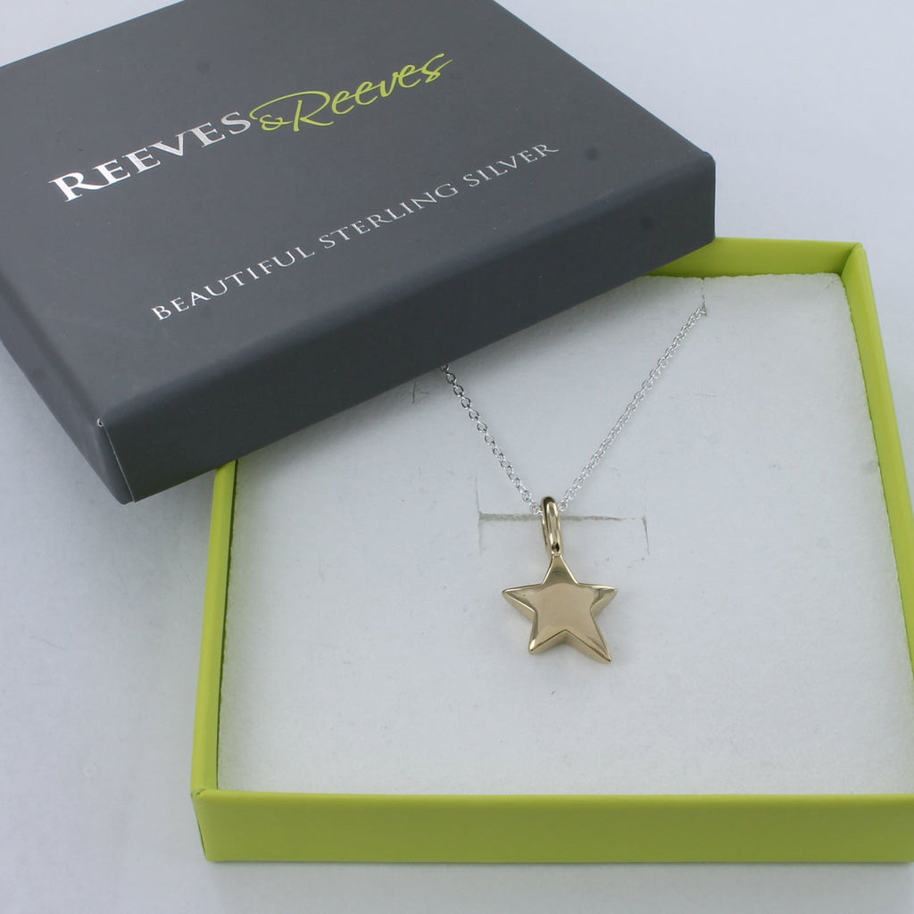A solid silver star necklace with 18ct gold plating, hung on a silver chain and shown in a Reeves & Reeves gift box.