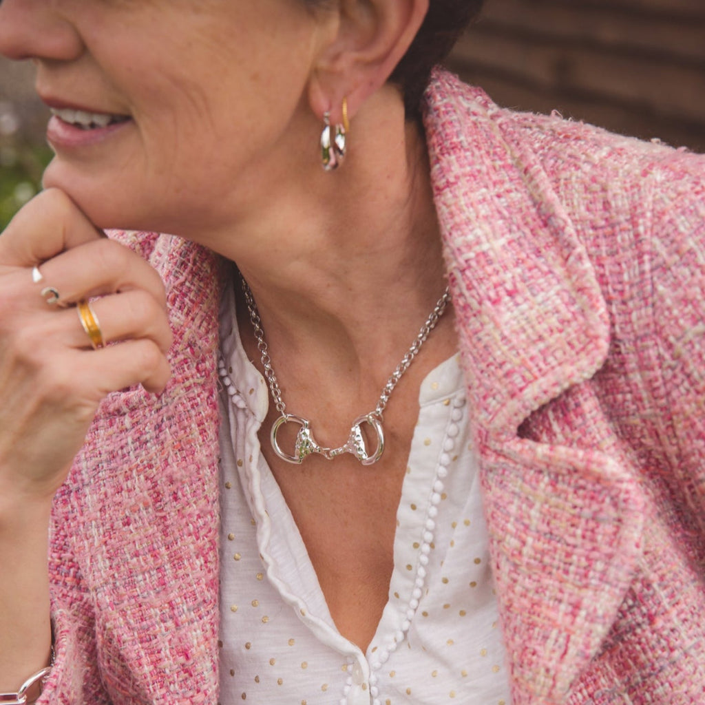 A sterling silver Supersize Snaffle Necklace with hammered detail on the central bit, sat on a circular chain and worn on a models neck.