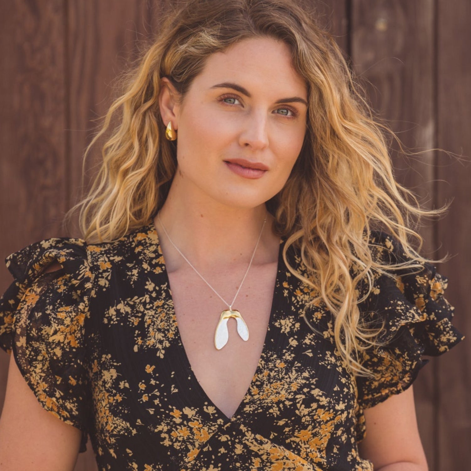 A sterling silver supersize sycamore with 18ct gold plated detail, hung on a silver chain and worn on a model.