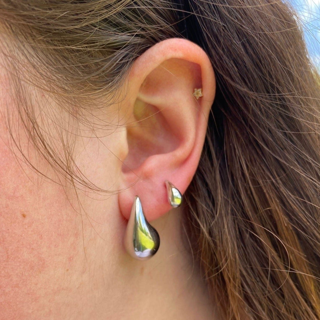 A lady wearing two teardrop style earrings in a 1st and 2nd piercing.