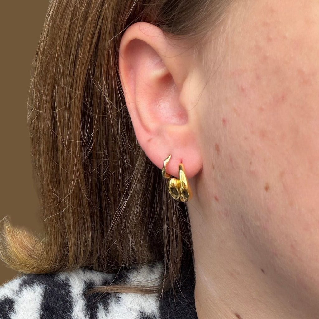 A pair of gold plated hoops with teardrop shapes curving round to meet at the front of the hoop. Worn in a ladies ear.