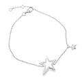 A sterling silver chain bracelet with a large star silhouette at the centre. Further along the chain is a smaller solid star charm hanging from the chain. The chain is finished with an adjuster and a lobster clasp.