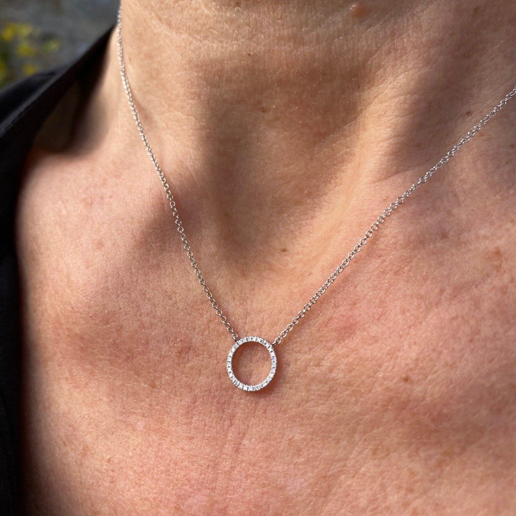 A 14k solid white gold ring necklace, encrusted with diamonds and worn on a model.