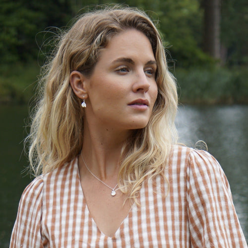 A pair of sterling silver ammonite drop earrings, worn on a model with the matching necklace.