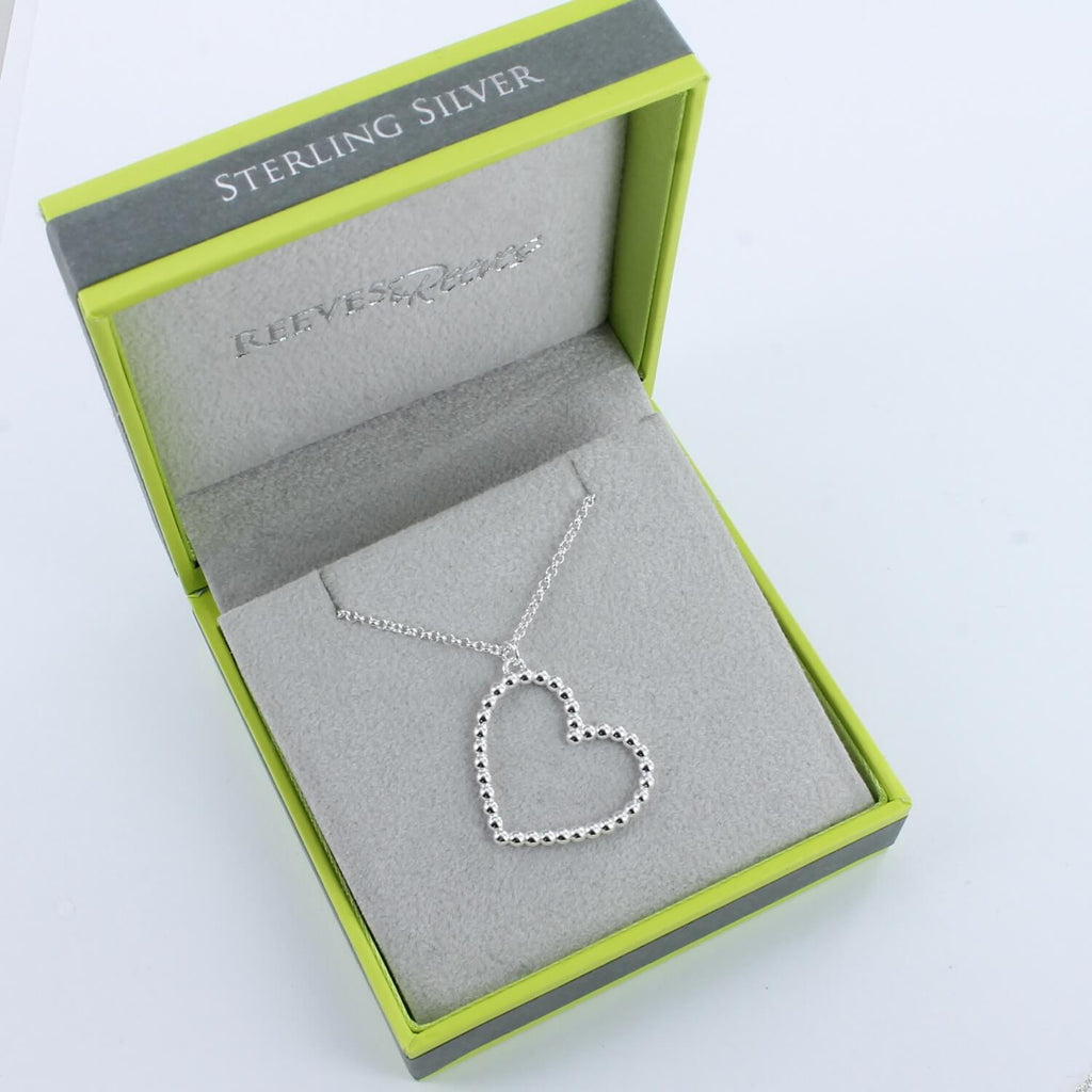 A Sterling Silver Heart silhouette pendant, made up of small silver beads and hung on a silver chain. Shown in a Reeves & Reeves grey and green gift box.
