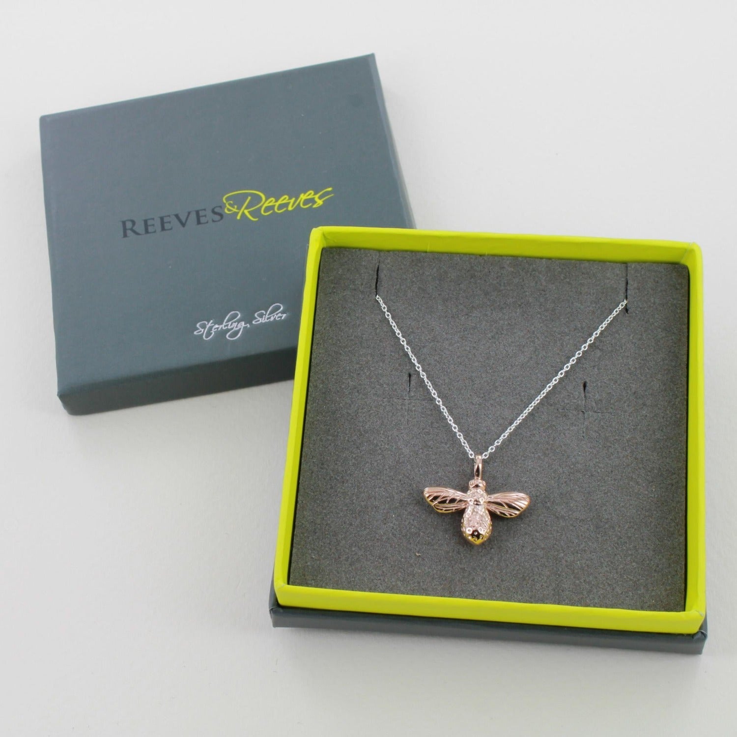 Sterling Silver and rose gold plate bumble bee necklace on a silver adjustable chain, shown in a grey and green reeves and reeves branded gift box.