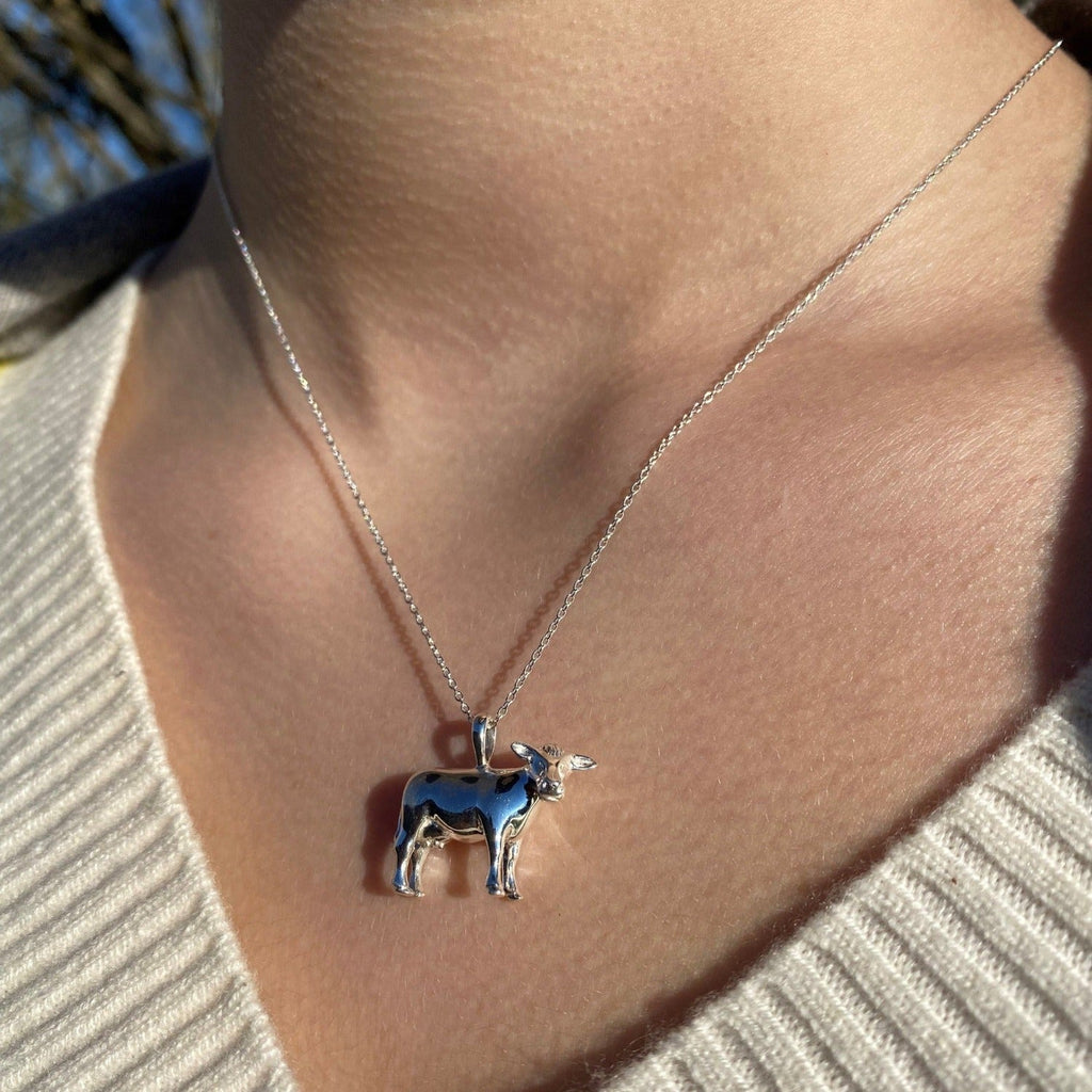 Sterling Silver Cow Pendant on a silver adjustable chain and worn on a models neck.