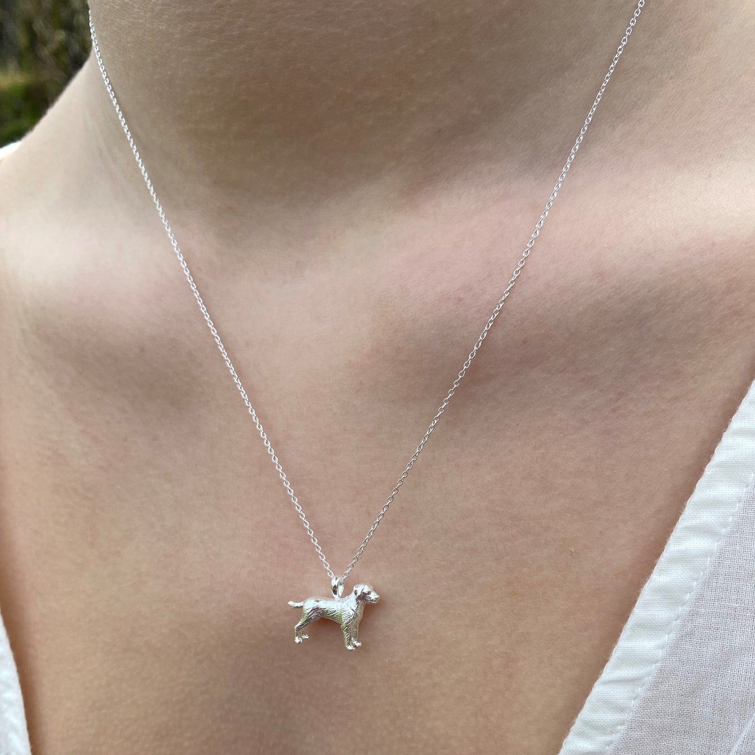 A Sterling Silver Labrador Dog Necklace, hung on a silver chain and worn on a models neck.