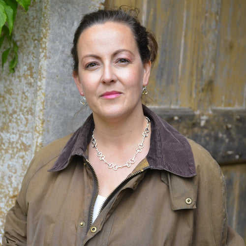 A Sterling Silver continuous snaffle necklace, shown on a model wearing a Barbour jacket.