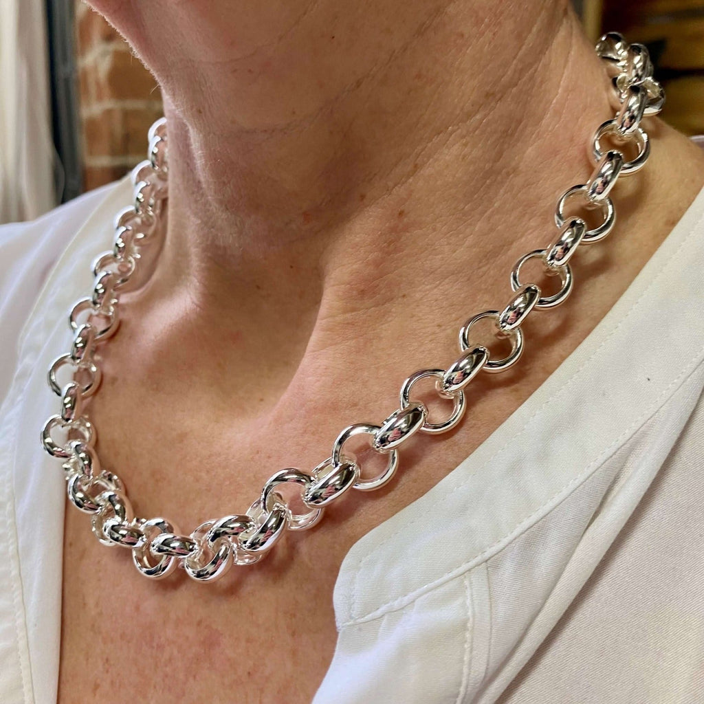 A sterling silver classic statement link necklace in a continuous design, worn on a models neck.