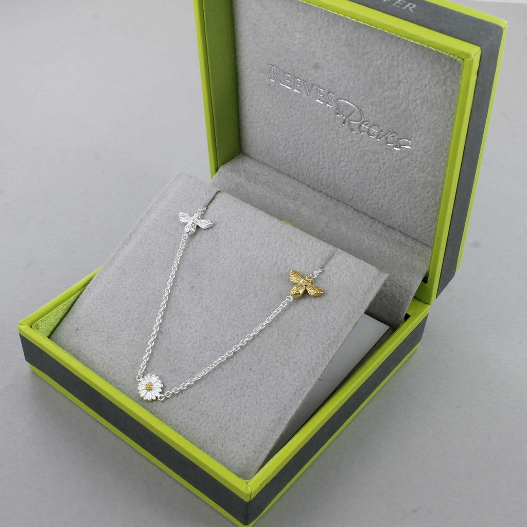 A Sterling Silver chain necklace with a silver bee, gold plated bee and a daisy spread evenly along the chain. Shown in a Reeves & Reeves grey and green gift box.