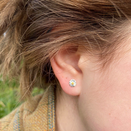 A sterling silver daisy stud earring with 18ct gold plate centre. Worn in a ladies ear.