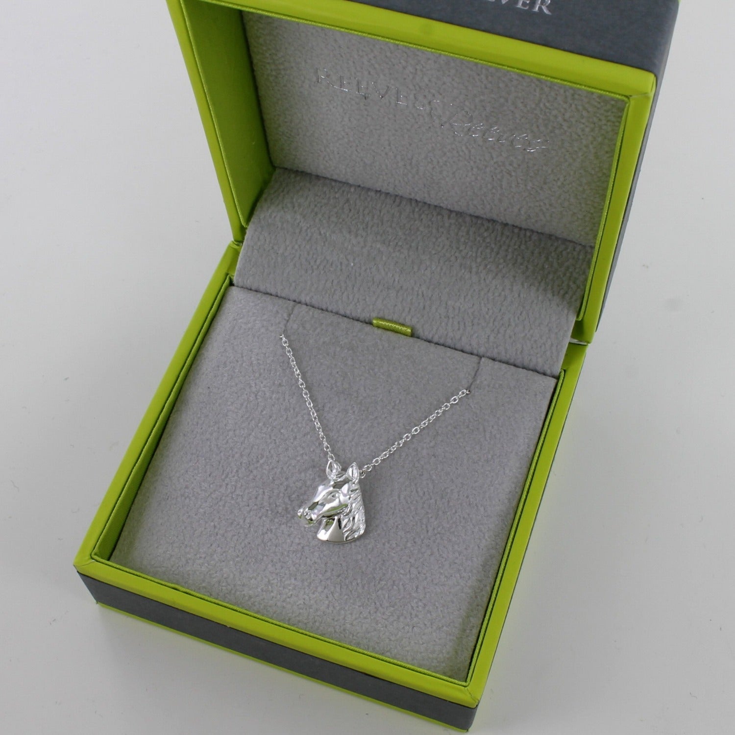 A Sterling Silver Horse Head Necklace on a silver chain and shown in a Reeves & Reeves grey and green branded gift box.