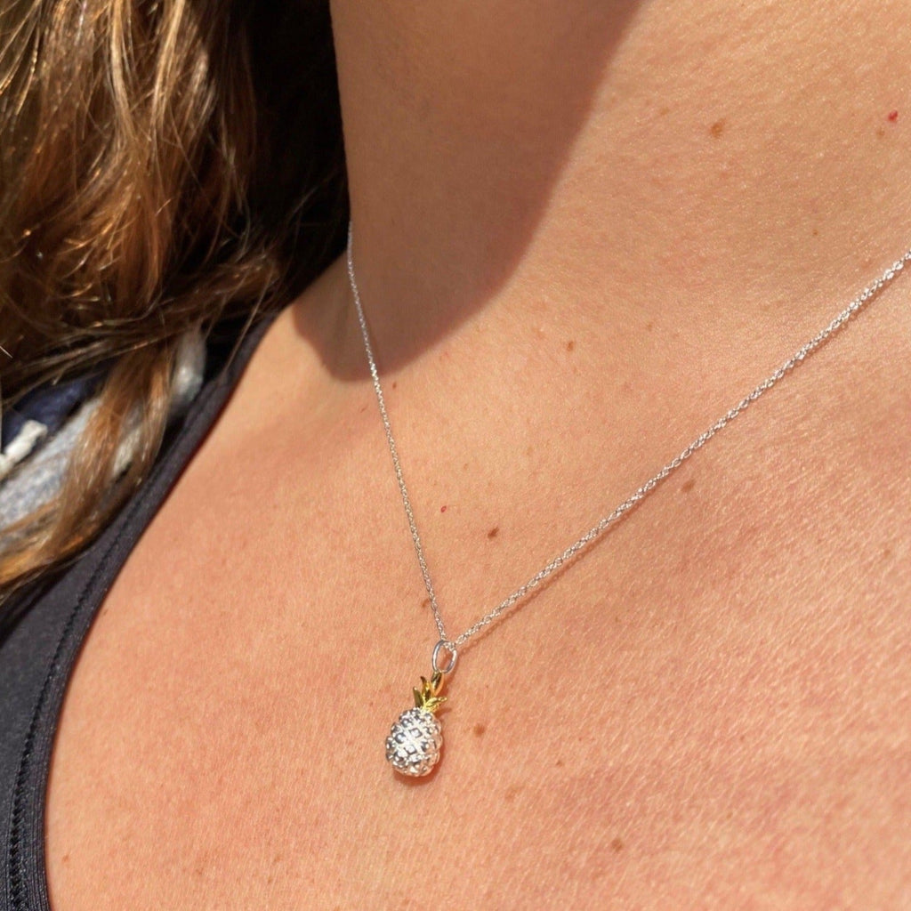 A Silver and gold plated Pineapple Necklace, worn on a models neck.
