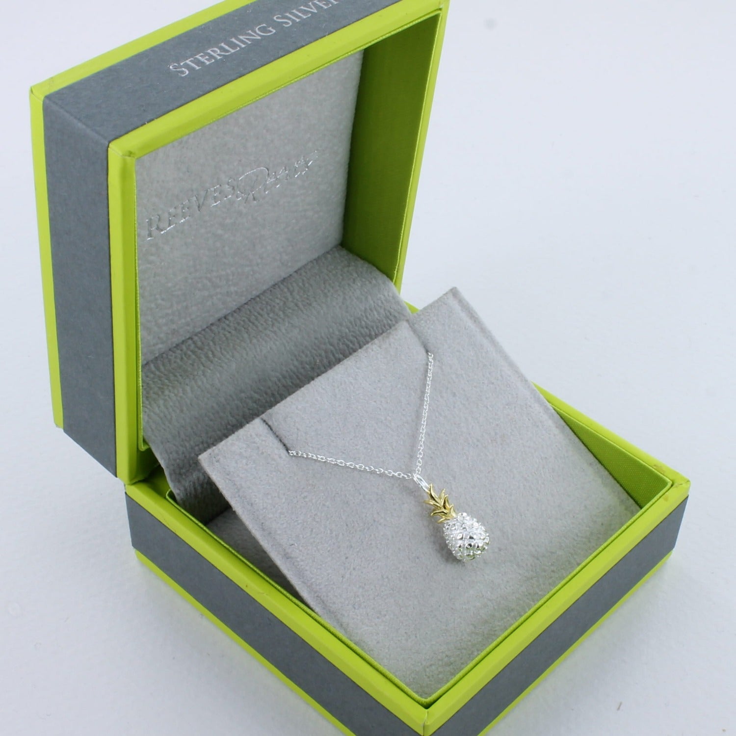 A Sterling Silver and gold plated Pineapple Necklace on a silver chain and shown in a Reeves & Reeves grey and green gift box.