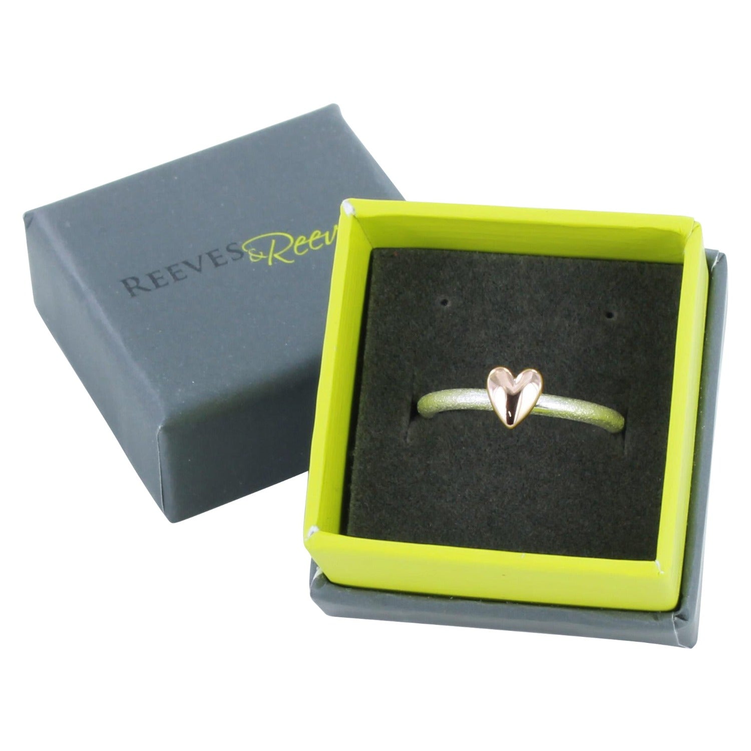 A silver band ring with a rose gold plated heart, shown in a Reeves & Reeves branded box.