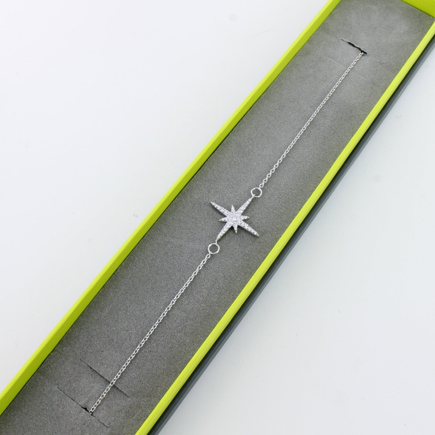 Sterling silver chain bracelet with an eight point star filled with cubic zirconia stones shown in a grey and green Reeves & Reeves branded box.