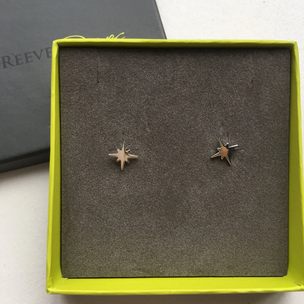 A pair of sterling silver eight point star earrings with a high shine finish and shown in a Reeves & Reeves gift box.