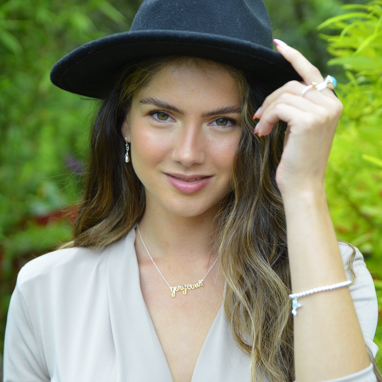 A sterling silver script necklace with the word 'gorgeous' written in half silver and half gold plate, hung centrally on a silver chain and worn on a model.