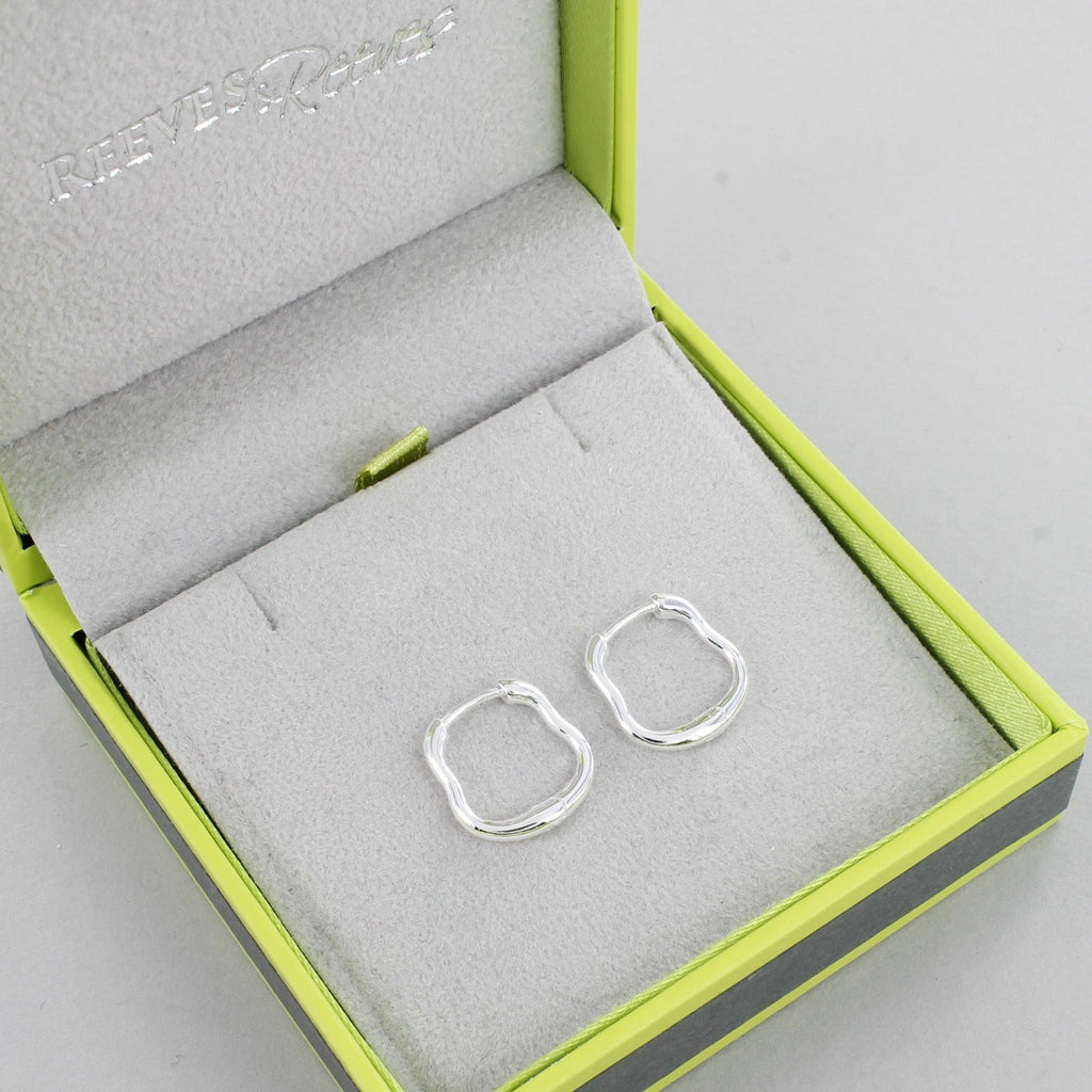 A pair of sterling silver hoop earrings with a wavy edge and shown in a Reeves & Reeves gift box.