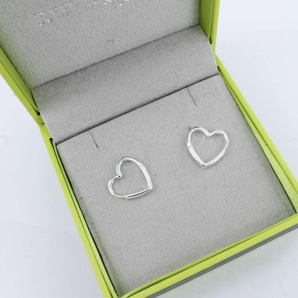 A pair of sterling silver heart shaped huggies, shown in a Reeves & Reeves gift box.