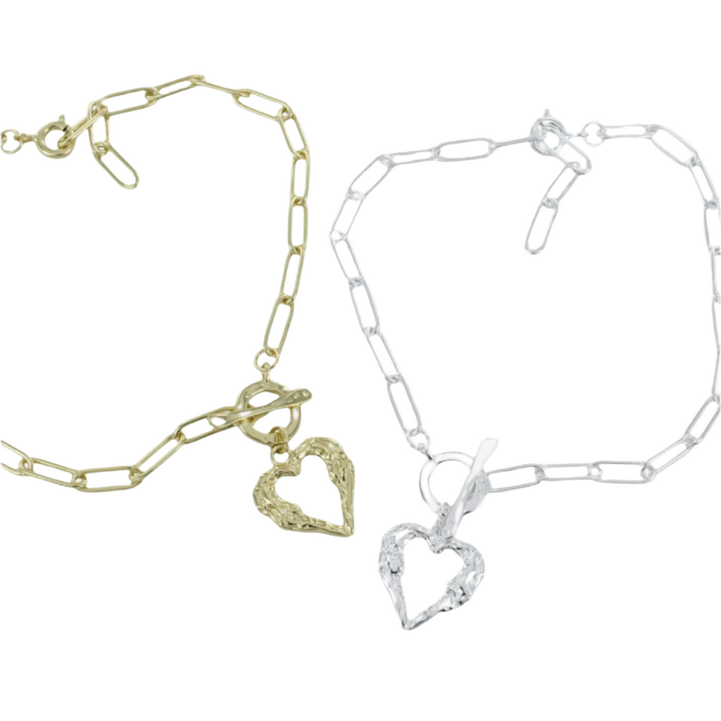 Two bracelets, one silver and one gold plate with a paperclip style chain and a t bar clasp. A textured heart silhouette hangs from the clasp as the central feature.