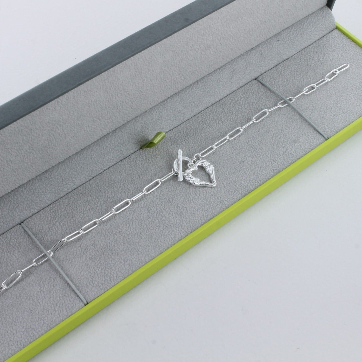 Sterling Silver paperclip style chain with a t bar clasp and a textured heart hanging from the clasp.