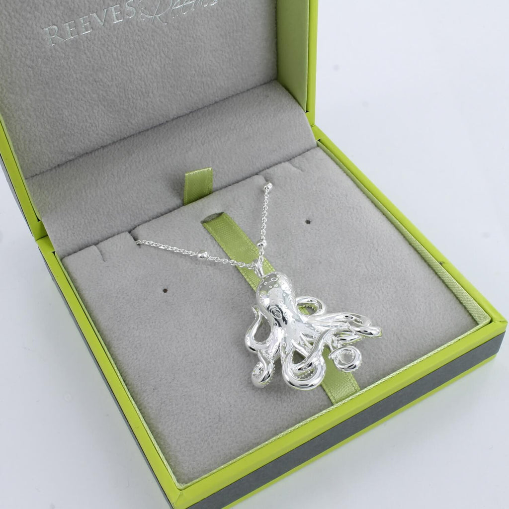 A sterling silver large octopus pendant with detailed finish, hung on a silver beaded chain and shown in a Reeves & Reeves gift box.