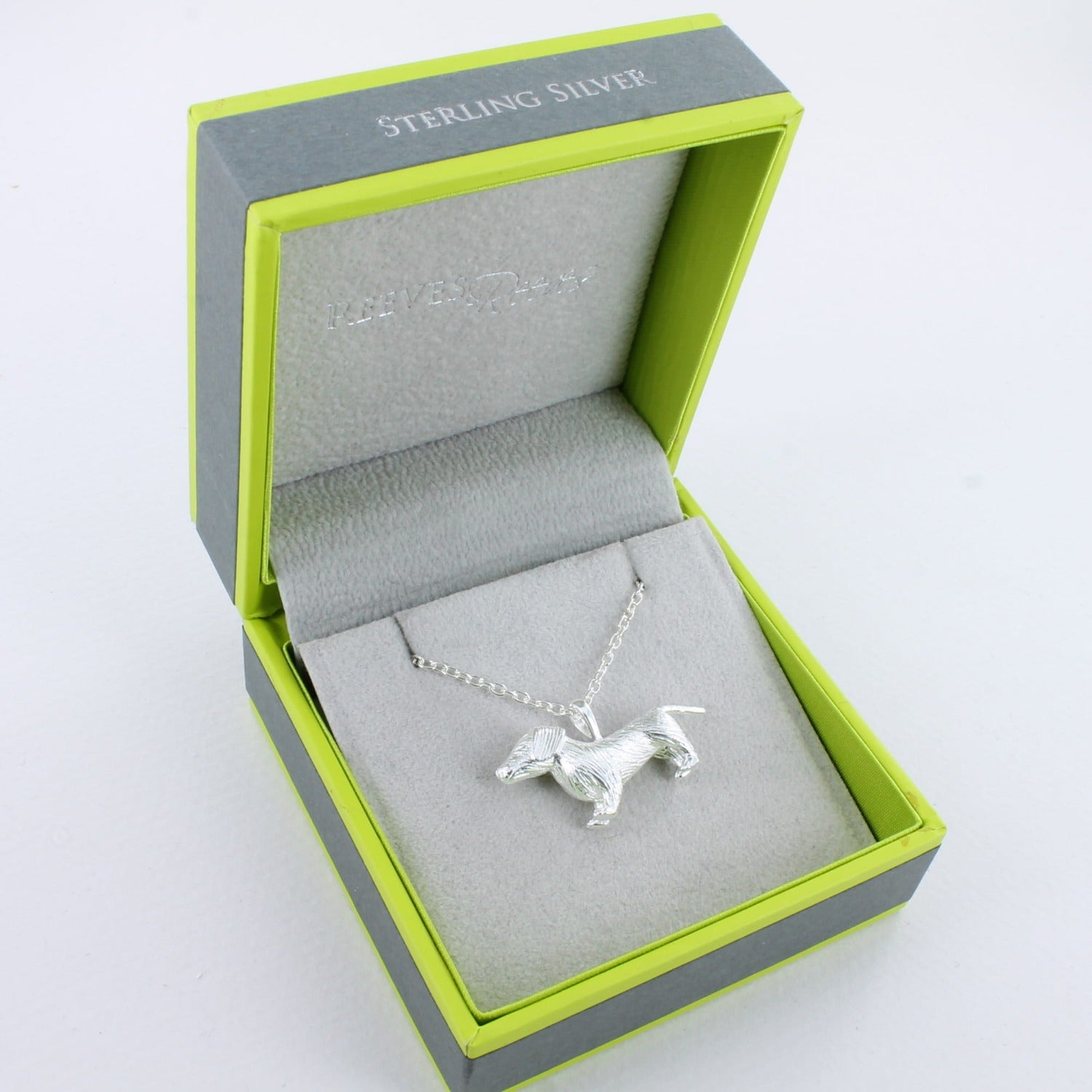 A sterling silver dachshund necklace, hanging on a silver adjustable chain and shown in a Reeves & Reeves gift box.