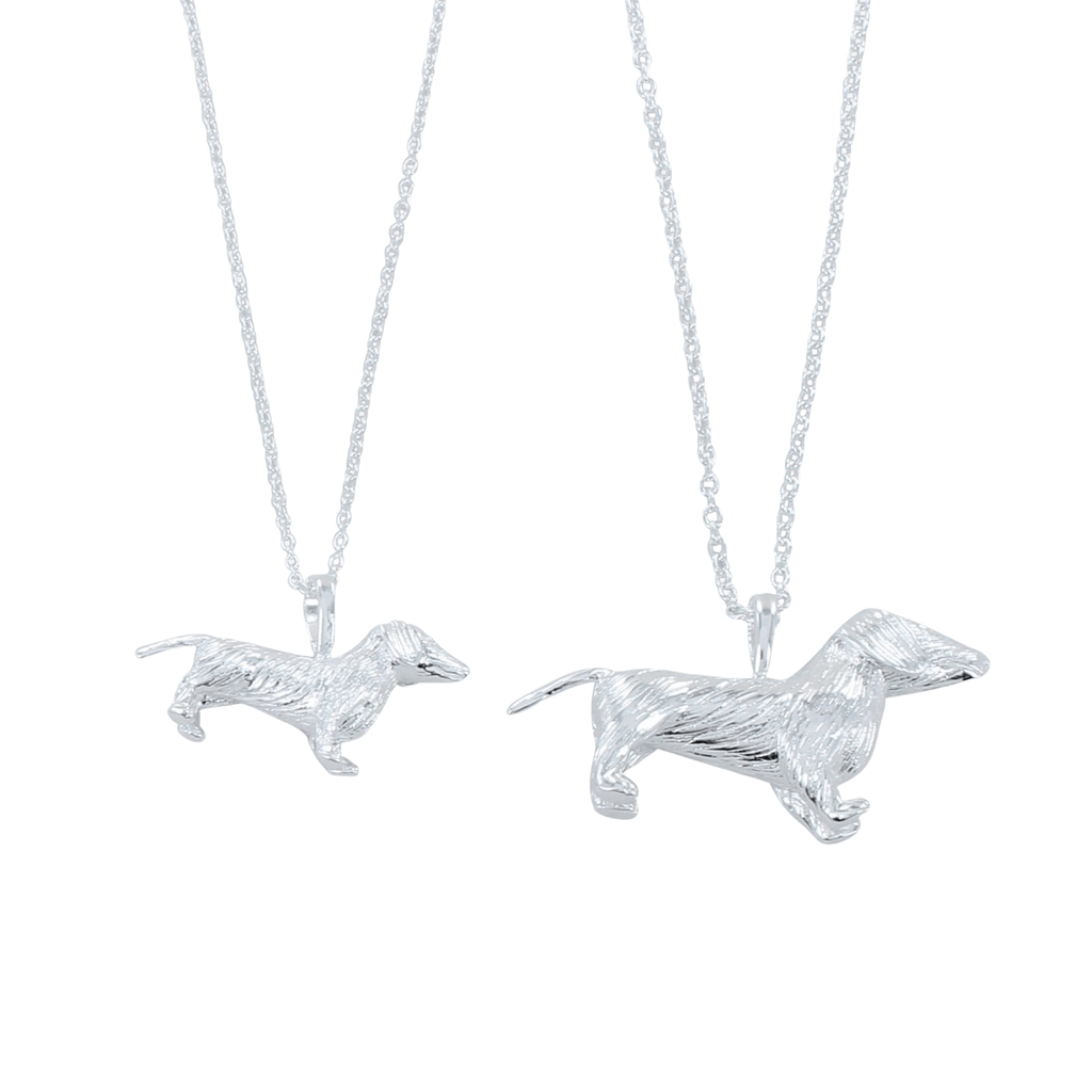 Two silver dachshund pendants, one smaller than the other in size, both hanging on silver adjustable chains.