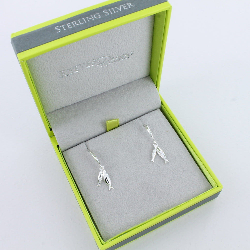 A pair of sterling silver drop style earrings with two little fish hanging from the bottom of a silver hook and shown in a Reeves & Reeves gift box.