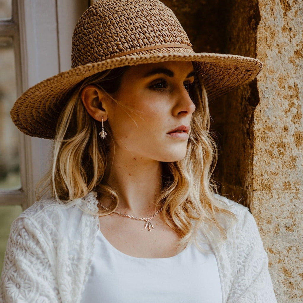 A model wearing a Little Fishes chain necklace with a pair of Turtle drop earrings.