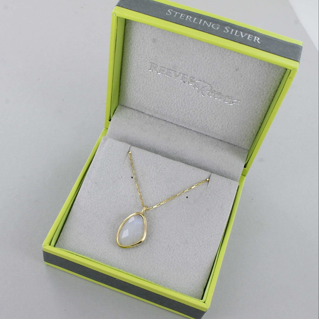 A moonstone necklace, set in gold plating and hung on a gold box chain. Shown in a Reeves & Reeves branded gift box.
