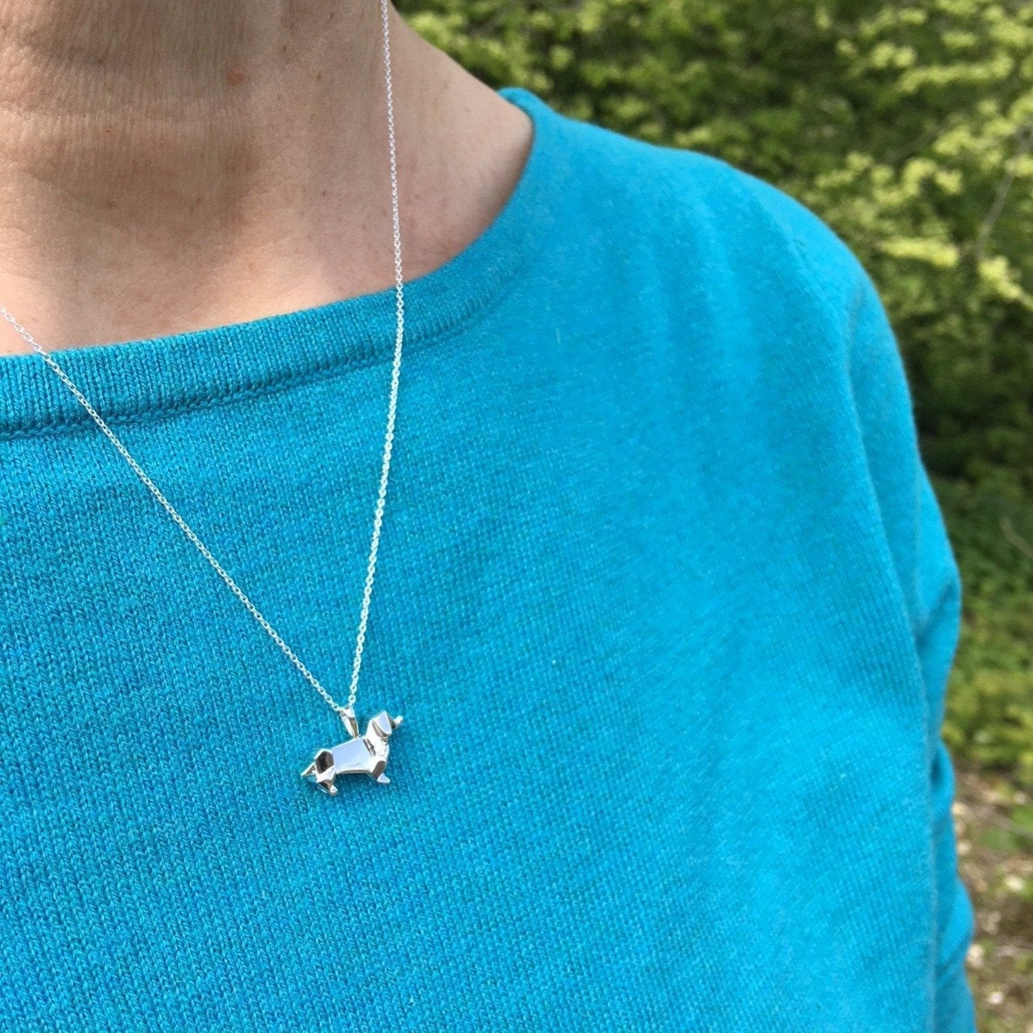 Sterling Silver Dachshund pendant in an origami design, hanging on a silver adjustable chain worn on a model.