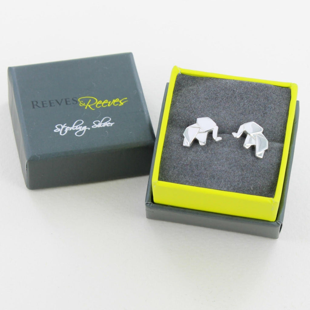 A pair of silver stud earrings in the shape of an elephant in an origami style. Shown in a Reeves & Reeves gift box.