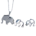 A pair of sterling silver elephant stud earrings in an origami style. Pictured next to the matching necklace.