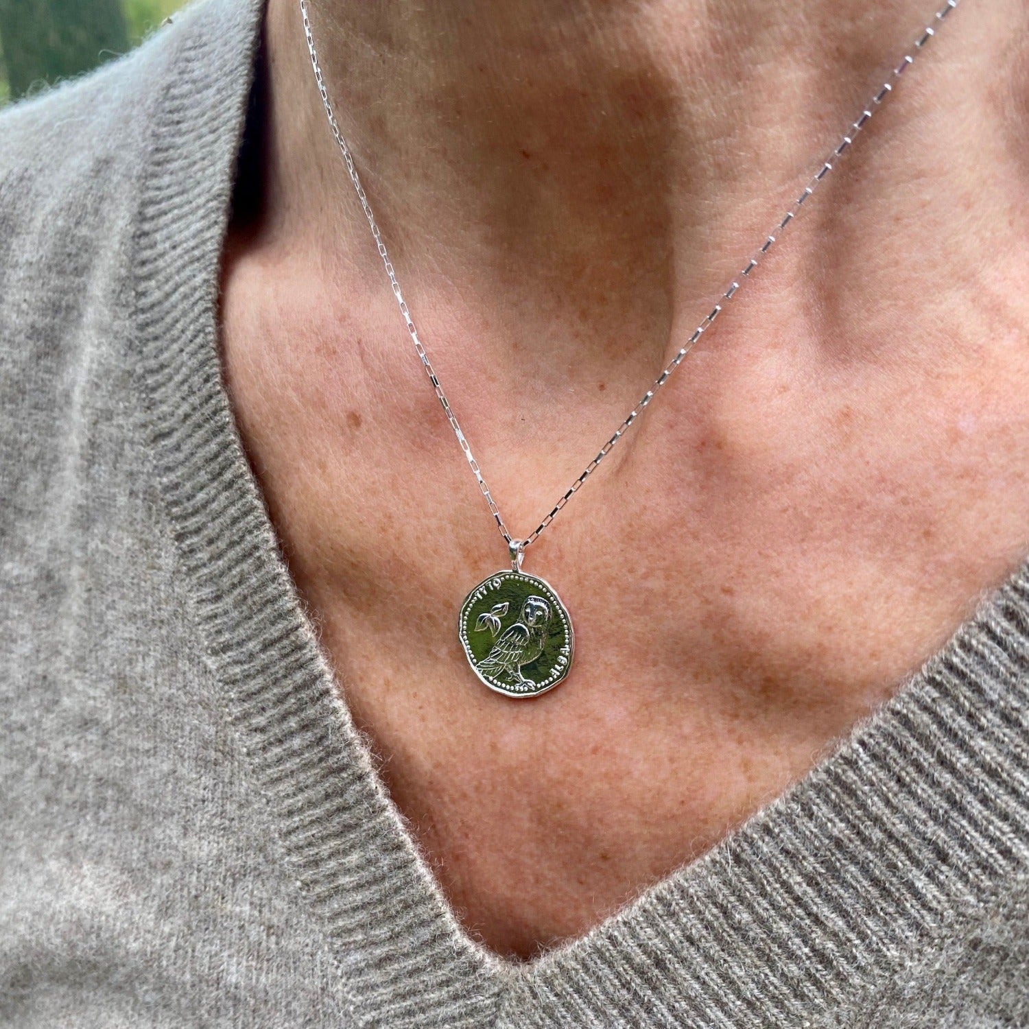 Silver Owl Coin Necklace hanging on a silver box style chain, shown worn on a models neck.