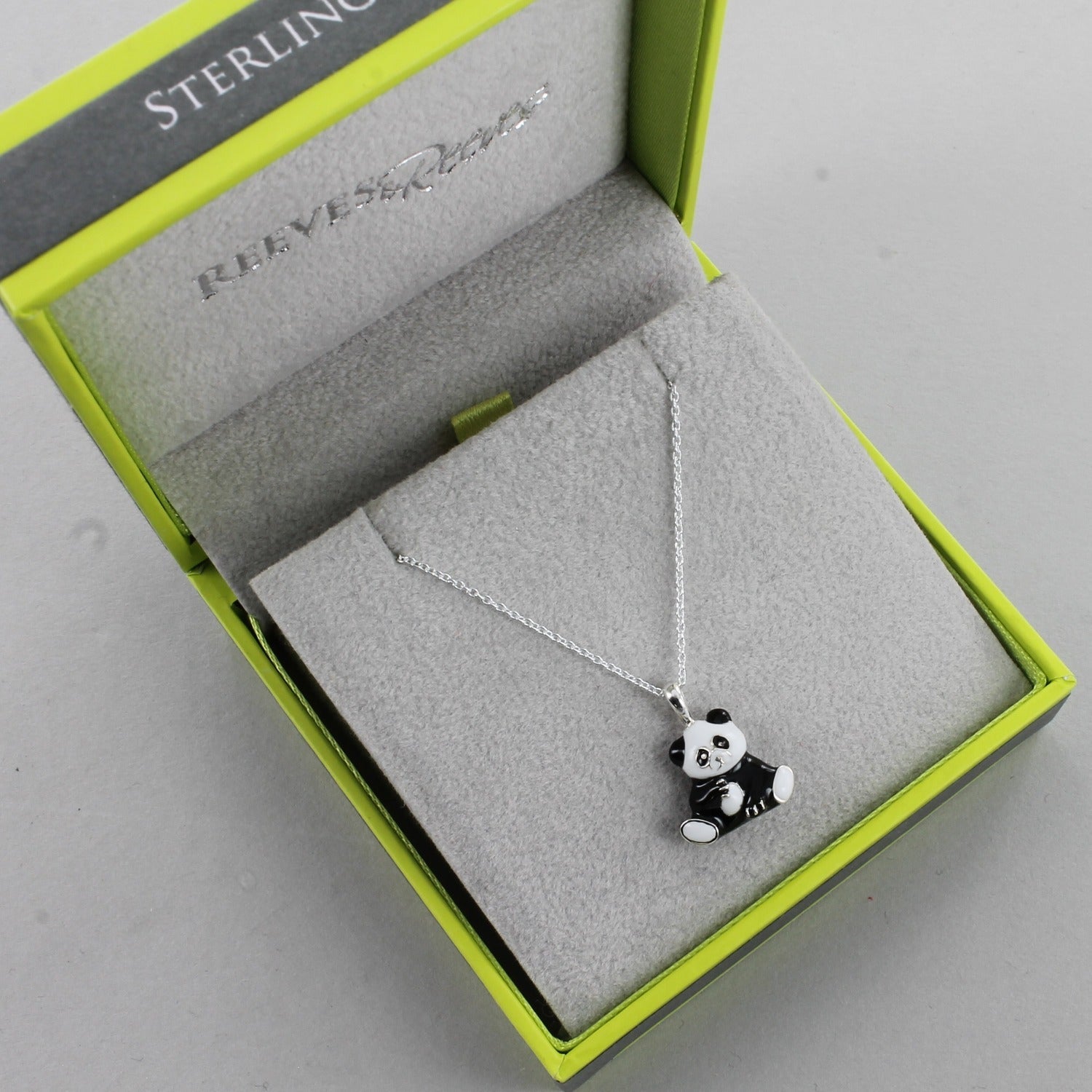 Sterling Silver Panda pendant with black and white enamel finish, hung on a silver chain and shown in a Reeves & Reeves grey and green branded gift box.