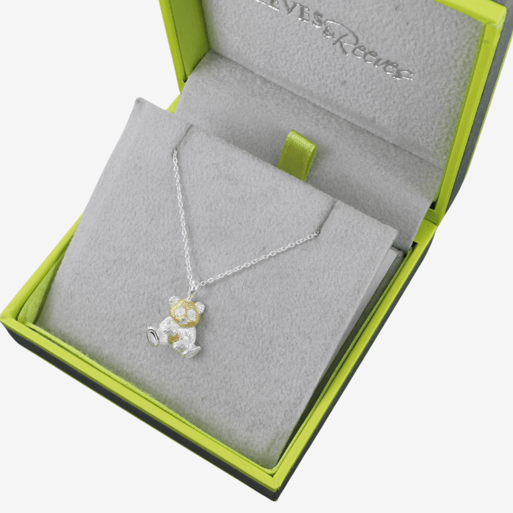 A sterling silver and gold plated Panda Necklace, hanging on a silver adjustable chain and shown in a Reeves & Reeves grey and green branded gift box.