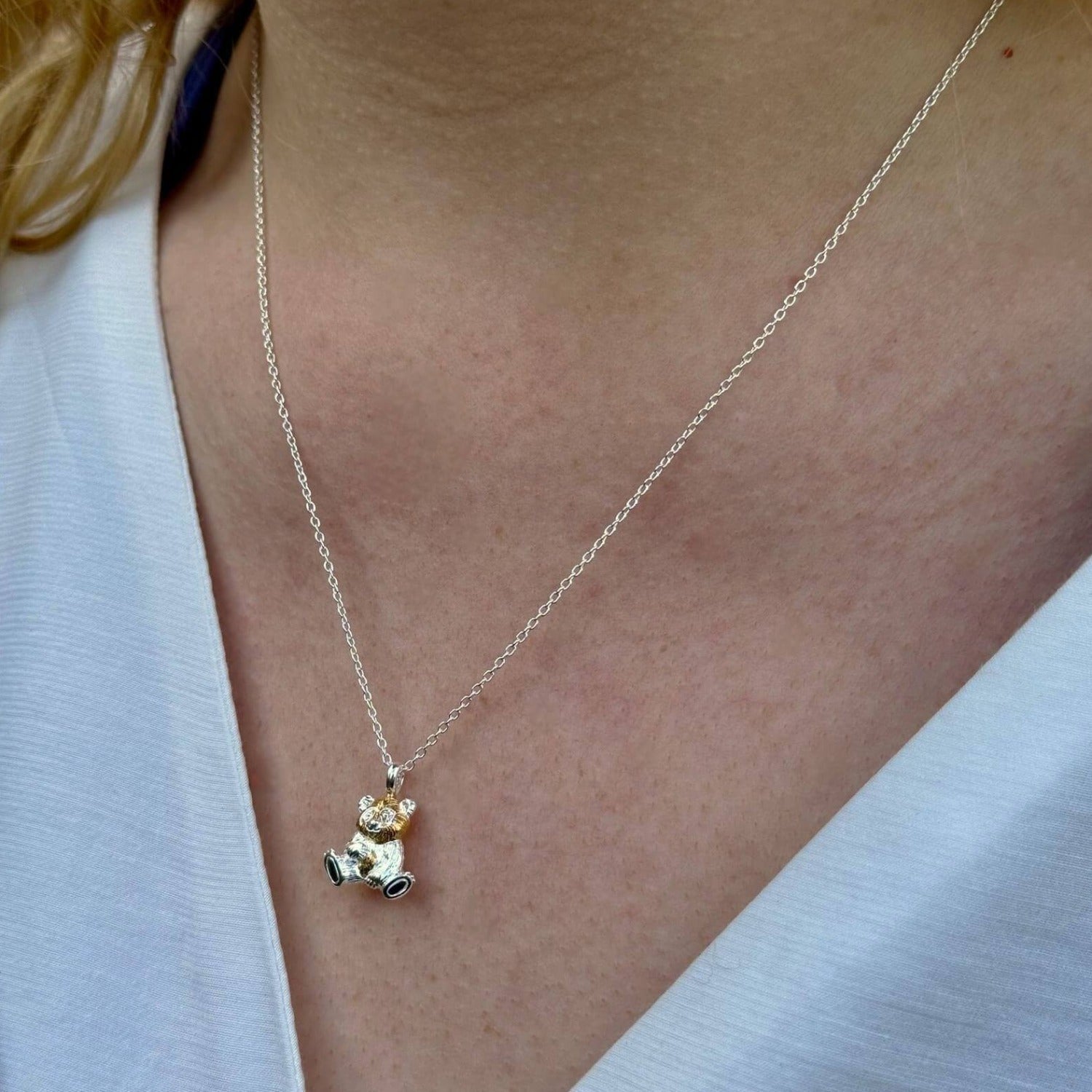 A sterling silver Panda necklace with 18ct gold plate finish on its face, hanging on a silver adjustable chain and worn on a model.