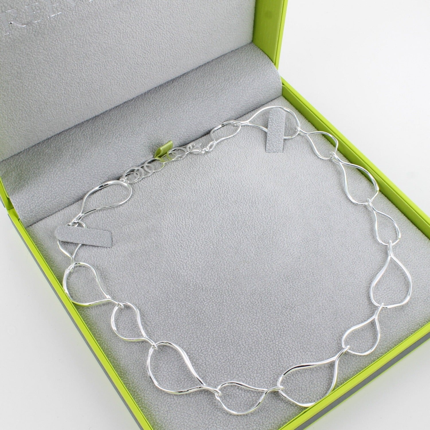 A sterling silver necklace comprising of pear drop shapes in varying sizes, in a continuous design around the neck, shown in a Reeves & Reeves gift box.
