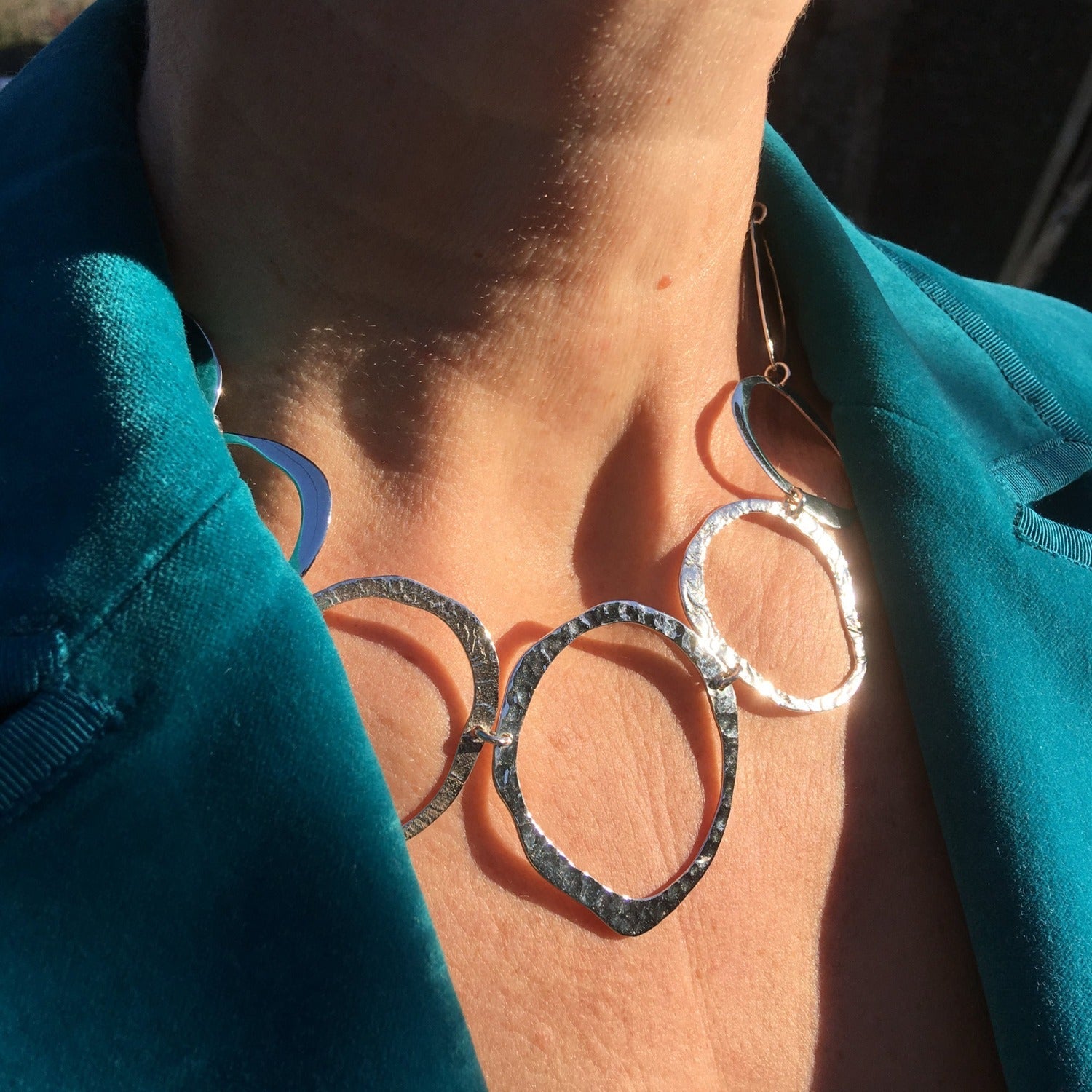 A sterling silver Pebbles Necklace, comprised of circular outlines, with varying textures in a continuous design around the neck. Worn on a model.