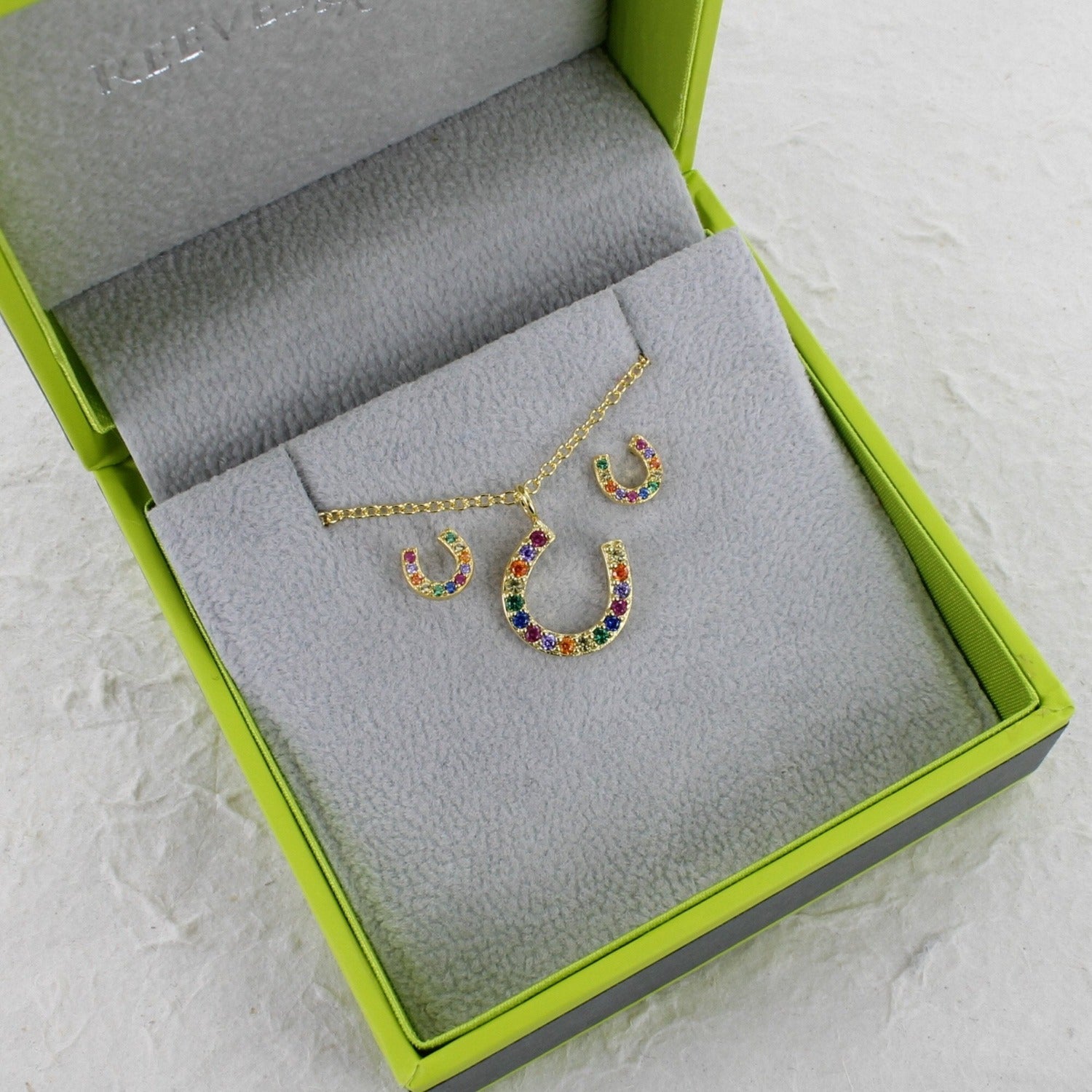 Rainbow Horseshoe Pendant with colourful cubic zirconia stones on a chain and shown in a box. Paired with matching stud earrings.