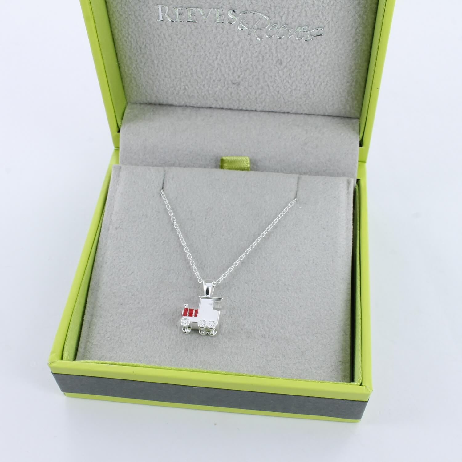 A sterling silver train necklace with red enamel detail, hung on a silver adjustable chain and shown in a Reeves & Reeves grey and green gift box.