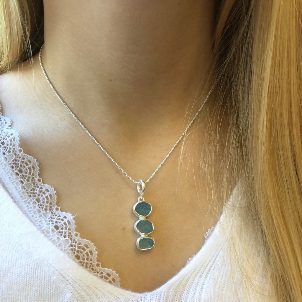 Three aqua marine stones, set in a vertical design in sterling silver, and hung on a silver rope style chain.