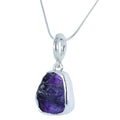 A rough cut tanzanite stone, set in sterling silver and hanging from a silver rope style chain.