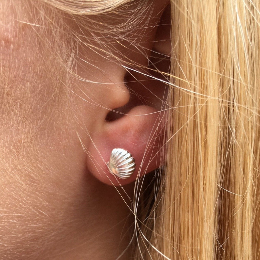 A Scallop Shell Stud Earring shown in a ladies ear.