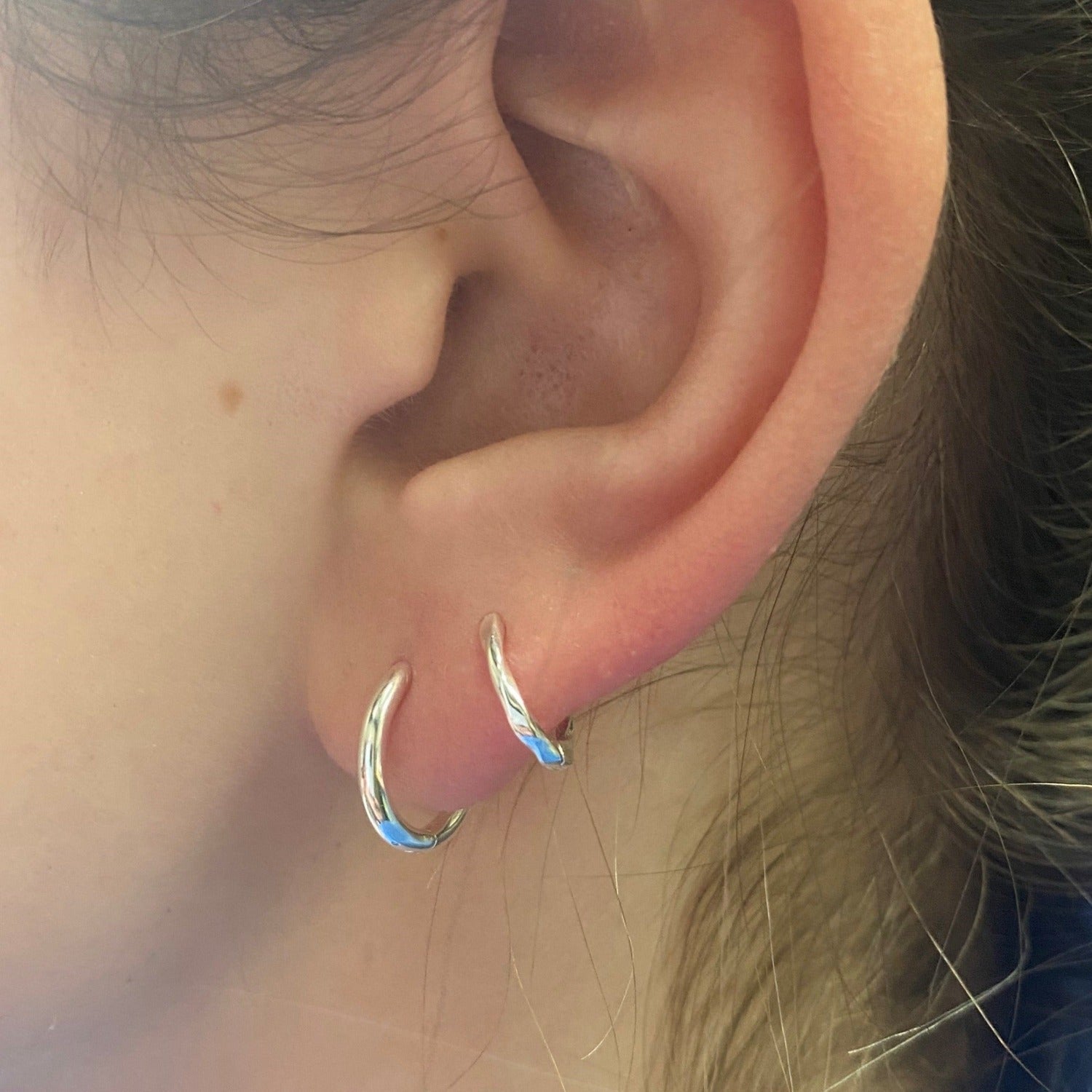 A sterling silver plain hoop with a smaller hoop in the second piercing.