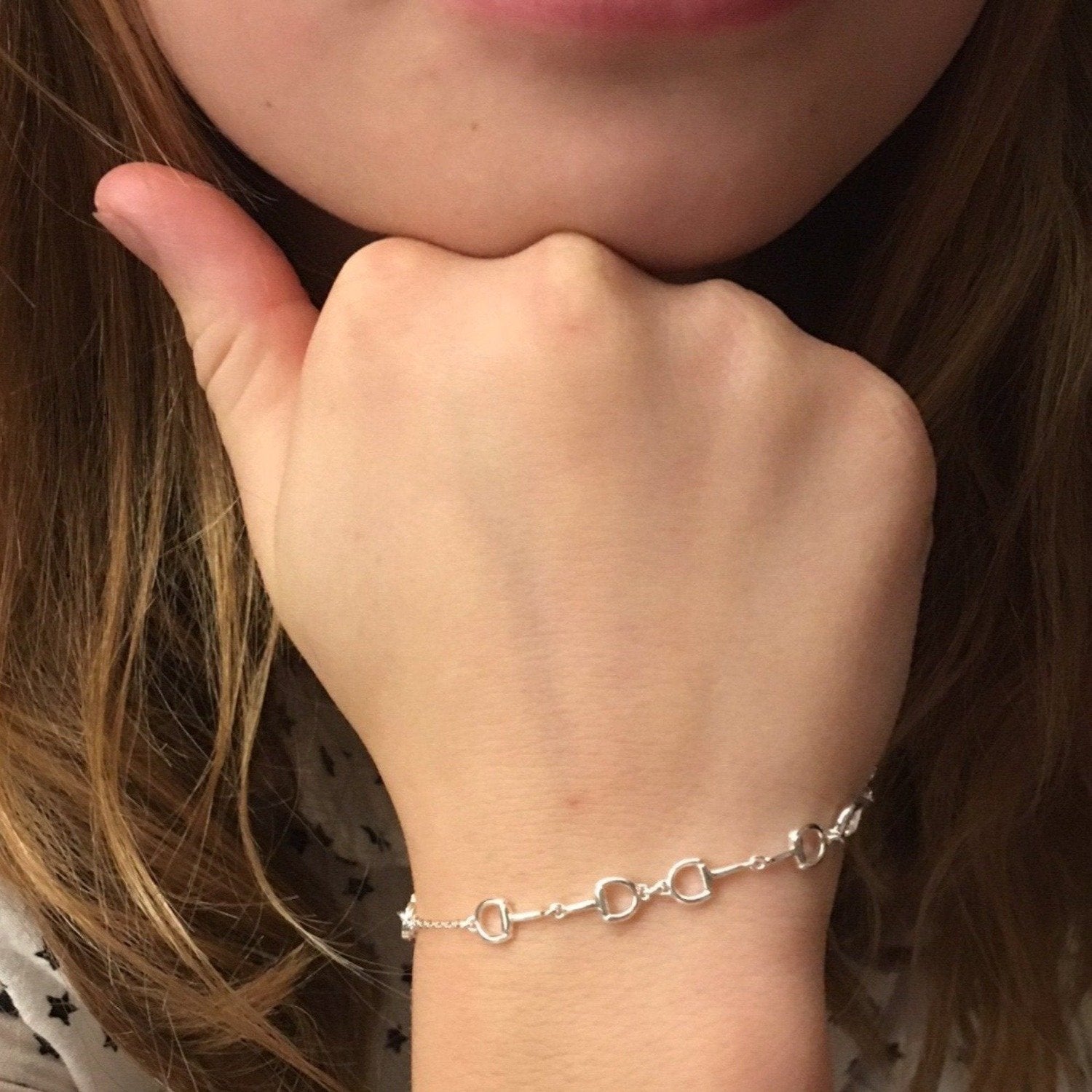 A Silver Snaffle Bracelet with interlocking snaffles worn on a wrist.